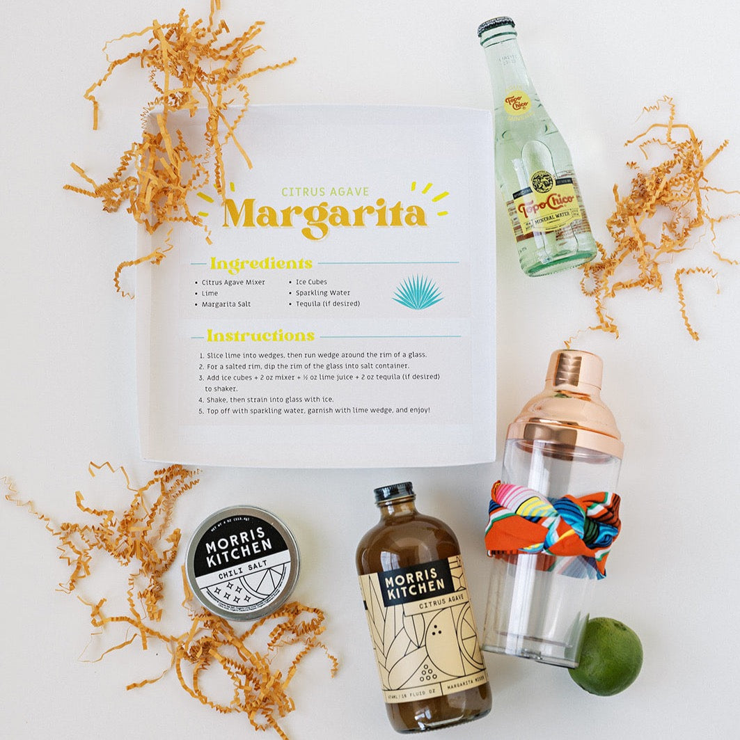 Whether you prefer it with sugar or salt, there’s one thing we can all agree on: margaritas make everybody happy! Cheers to a perfect gifting solution for any occasion.  Includes recipe & ingredients to make a zesty and refreshing margarita.  Gift contains:  Sparkling Water Citrus Agave Mixer Chili Salt Lime Rose Gold Cocktail Shaker Colorful Bandana Alcohol Not Included